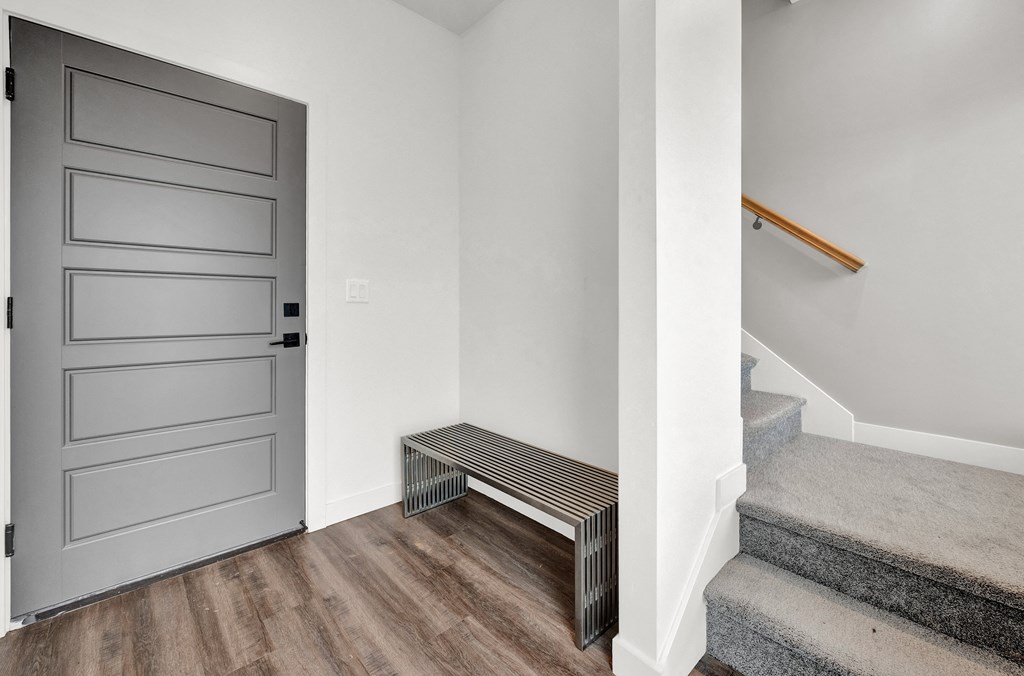 the front door of a home with stairs and a bench