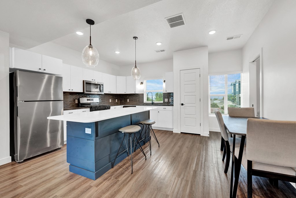 an open kitchen with a blue island and a stainless steel refrigerator