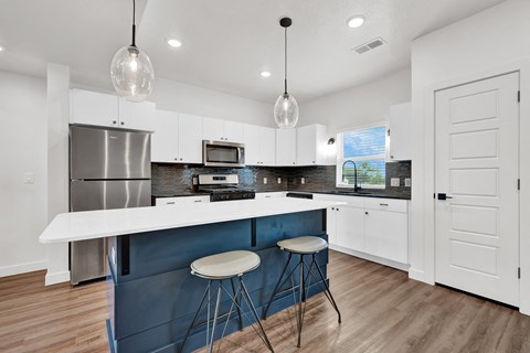 a kitchen with white cabinets and a blue island with two stools