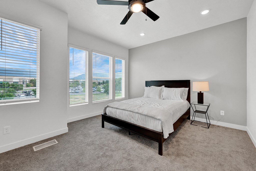 an empty bedroom with a bed and a ceiling fan