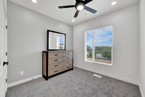 an empty room with a dresser and a ceiling fan