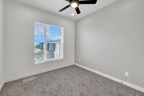 an empty room with a window and a ceiling fan