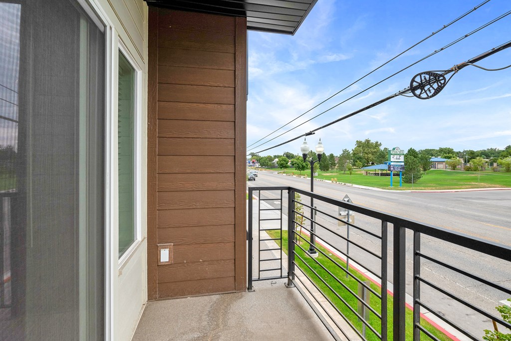 the view of the street from the balcony of a home with a metal railing