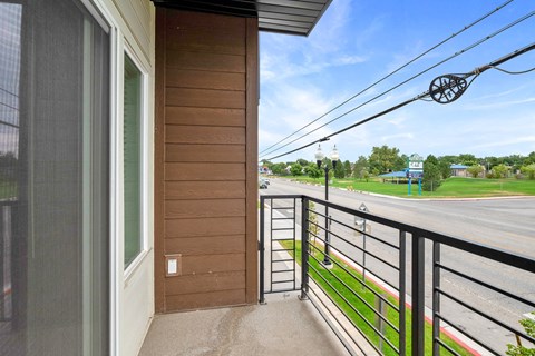 the view of the street from the balcony of a home with a metal railing