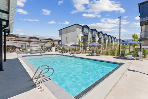 A swimming pool surrounded by a fence and apartment buildings.