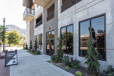 a building with a sidewalk and plants in front of it