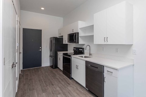 A kitchen with white cabinets and a black fridge.