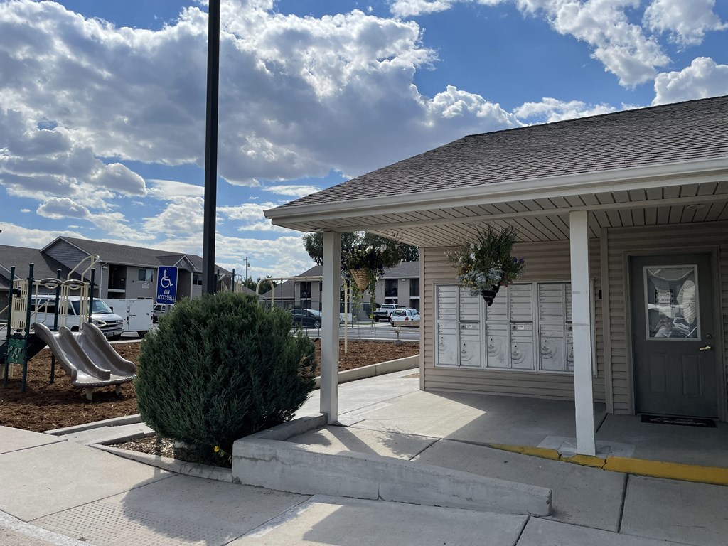 A small building with a porch and a sign on the sidewalk.