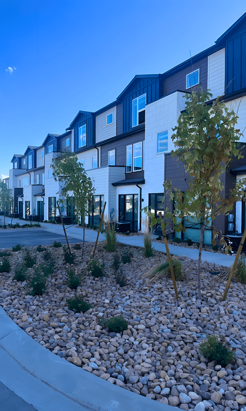 a view of the exterior of a building with gravel and trees