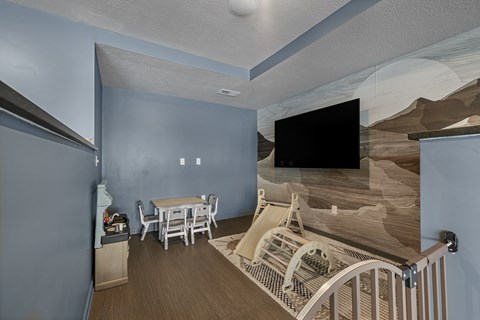 A room with a dining table and chairs, a television, and a staircase with a railing.