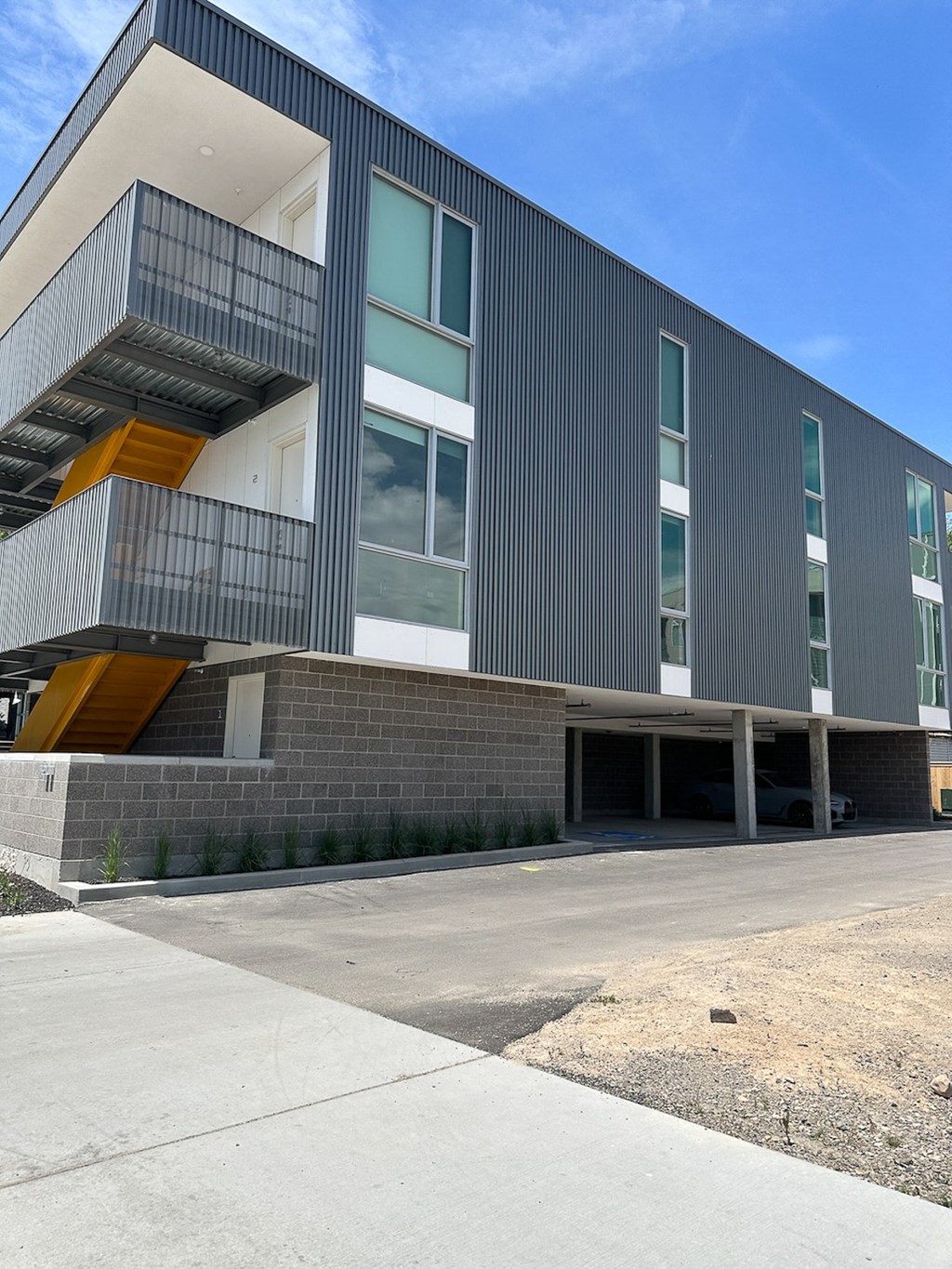 A modern building with a grey facade and a yellow staircase.