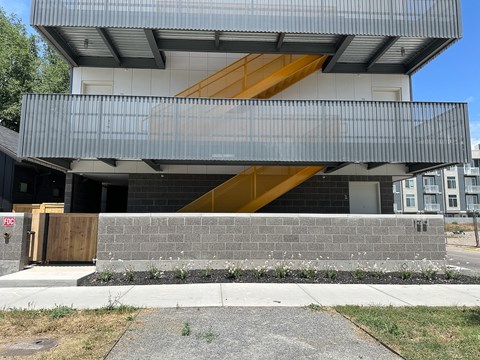 A modern building with a grey facade and a yellow staircase.