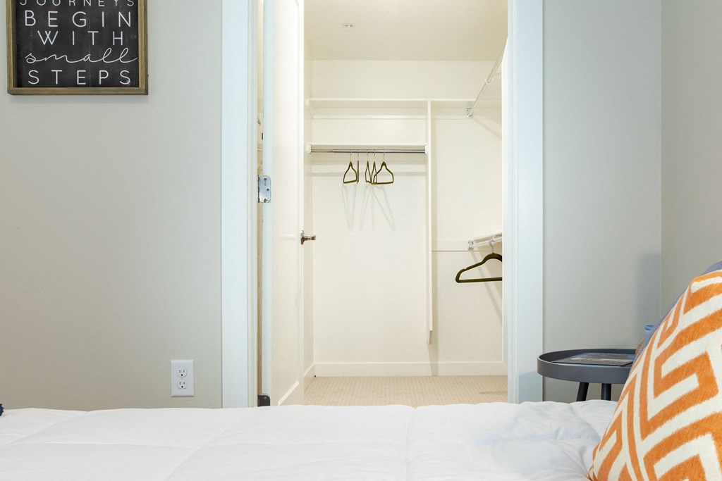 a bedroom with a white bed and a closet with hangers