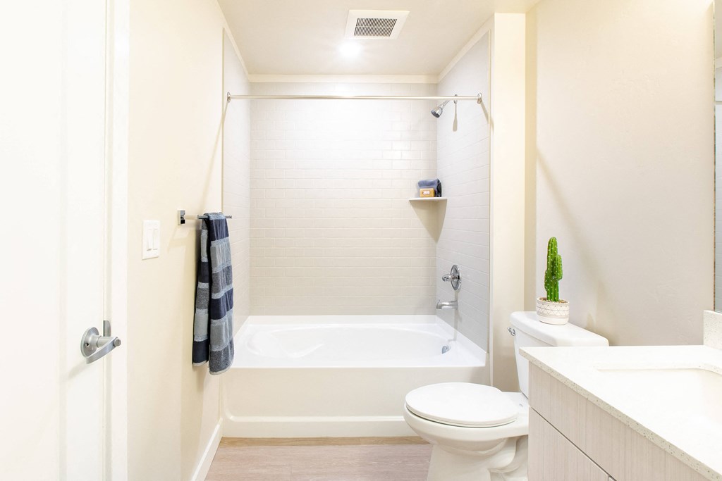 a white bathroom with a white toilet and a bath tub