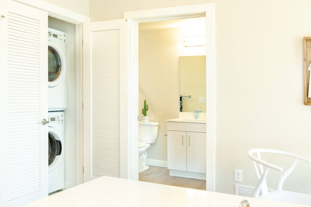 a white bathroom with a washer and dryer in it and a laundry room
