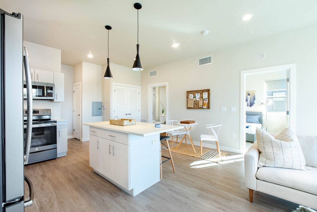 a kitchen with a white island and a living room with a couch and a table