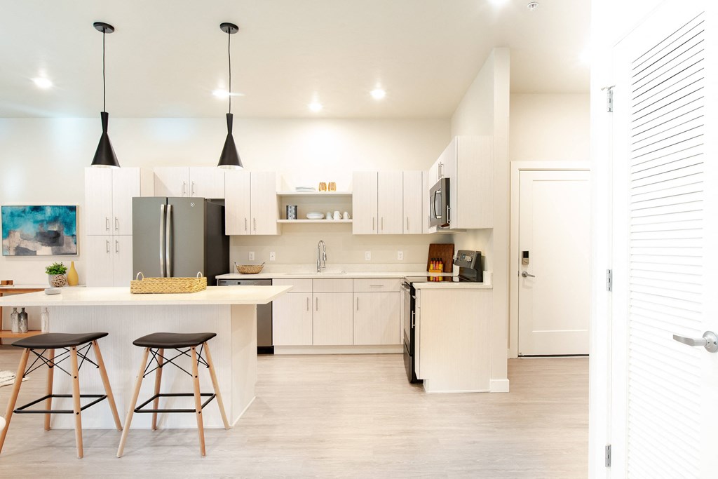 a kitchen with white cabinets and a bar with three stools