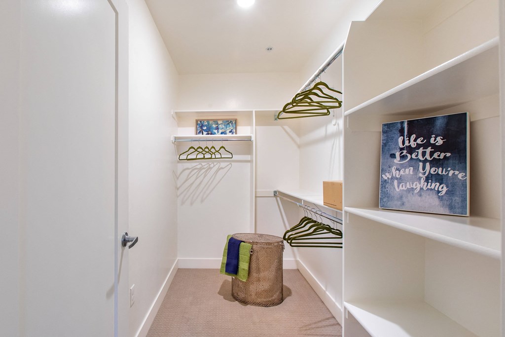 a walk in closet in a home with a door to a laundry room