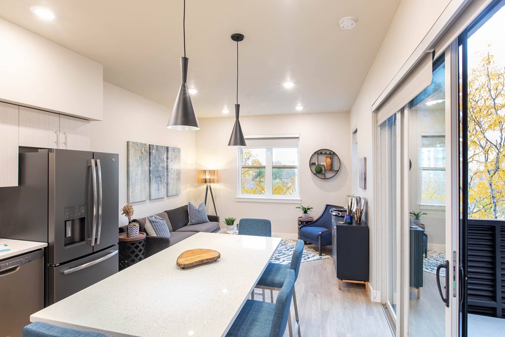 a kitchen and living room with a large white counter top and a refrigerator