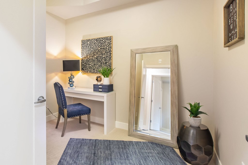 a bedroom with a desk with a mirror and a chair