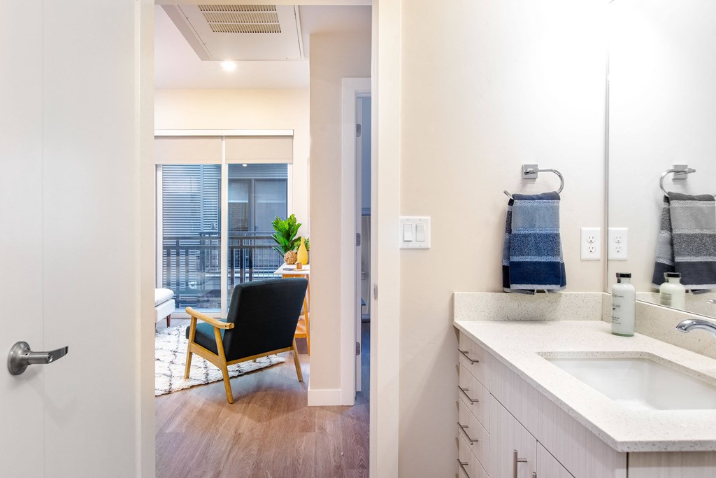 a bathroom with a sink and a mirror and a living room