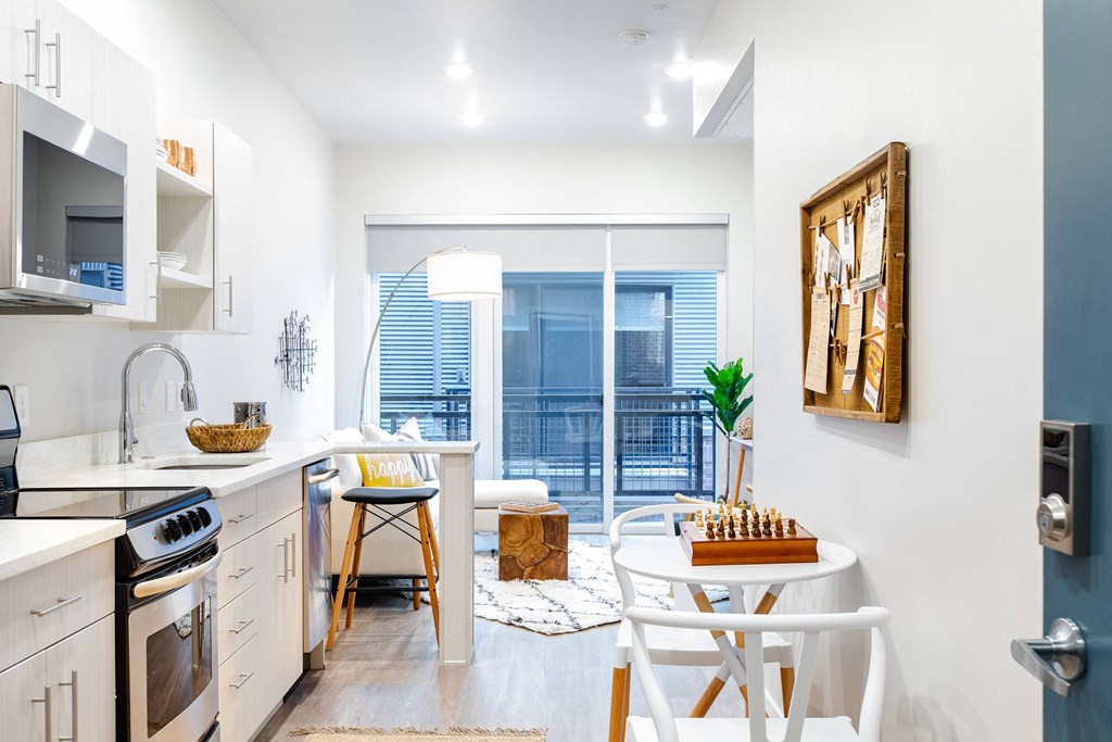 an open kitchen and living room with a sliding glass door to a balcony