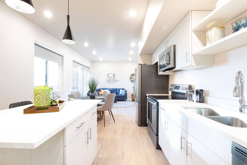 a kitchen and living room with white cabinets and a stainless steel sink