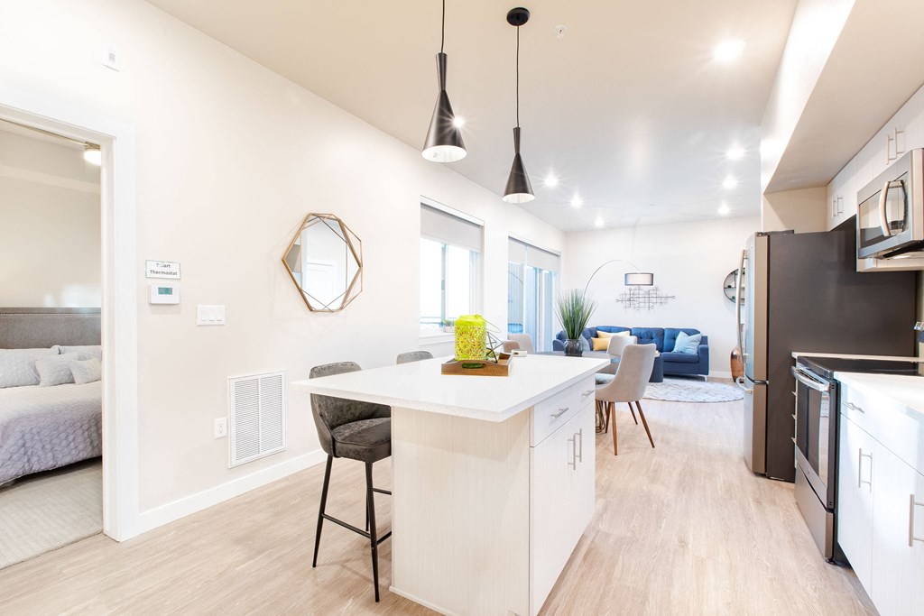 an open kitchen and living room with a white counter top and a dining room table