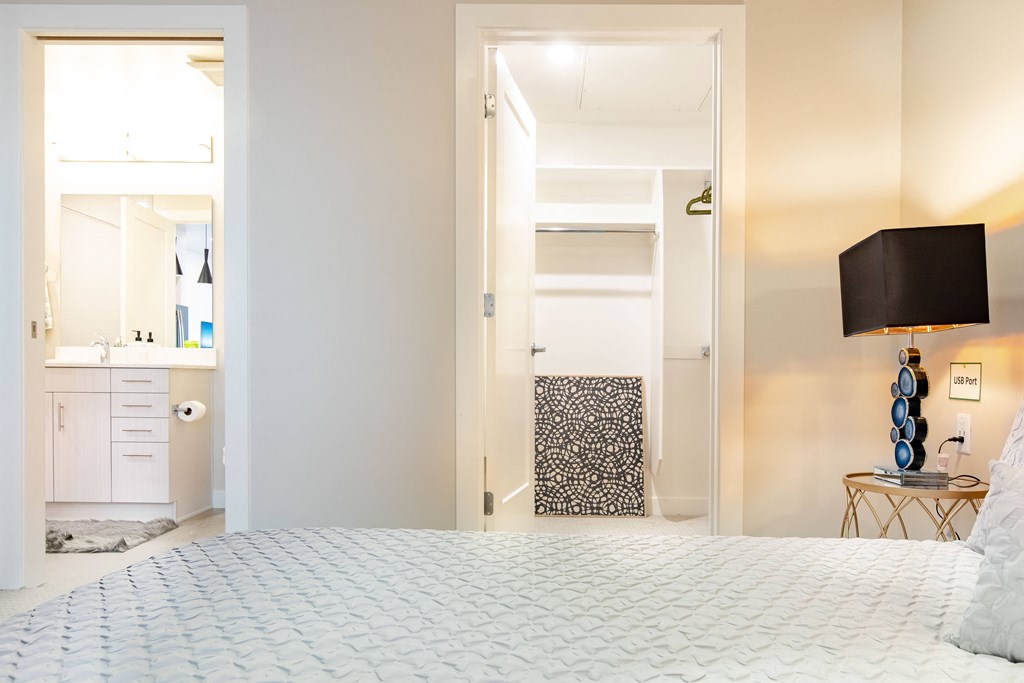 a bedroom with a white bed and a closet and a bathroom