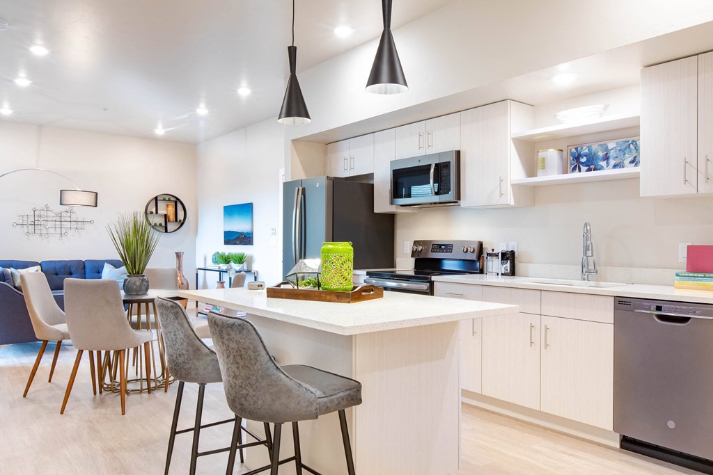 an open kitchen and living room with an island and chairs