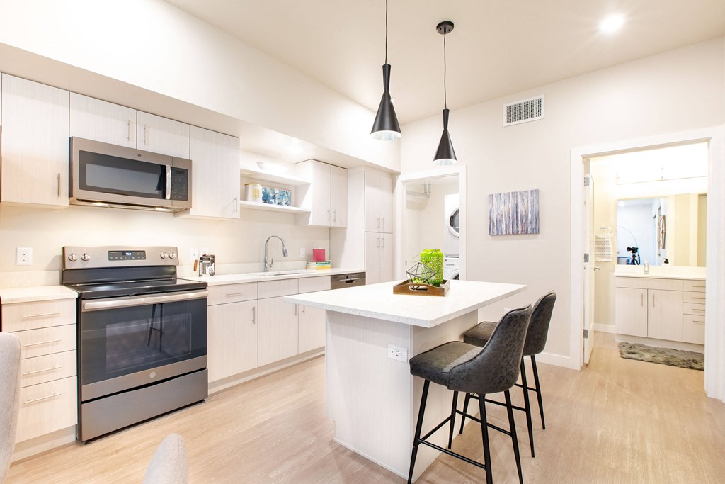 a kitchen with white cabinets and a white island with two stools