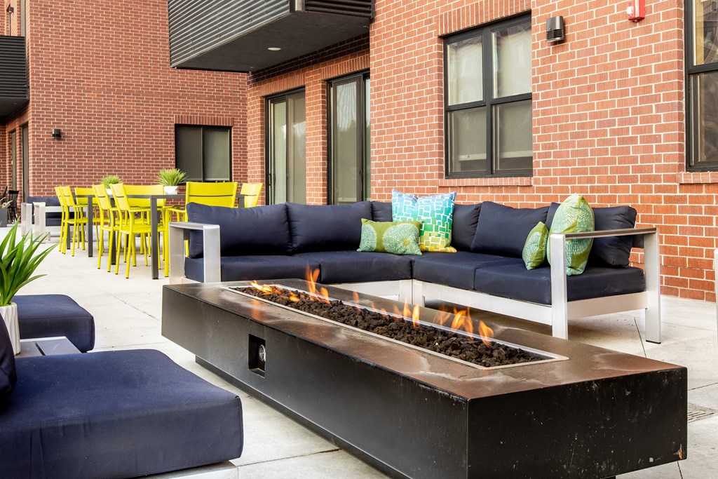a patio with couches and a fire pit in front of a building