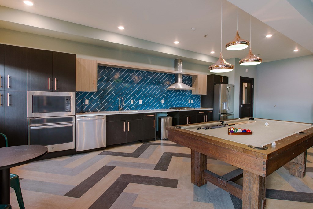a large kitchen with a pool table and stainless steel appliances