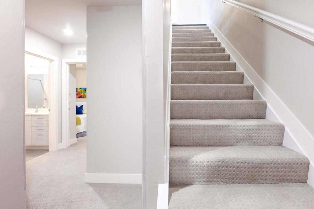 a set of stairs in a home with white walls and carpet