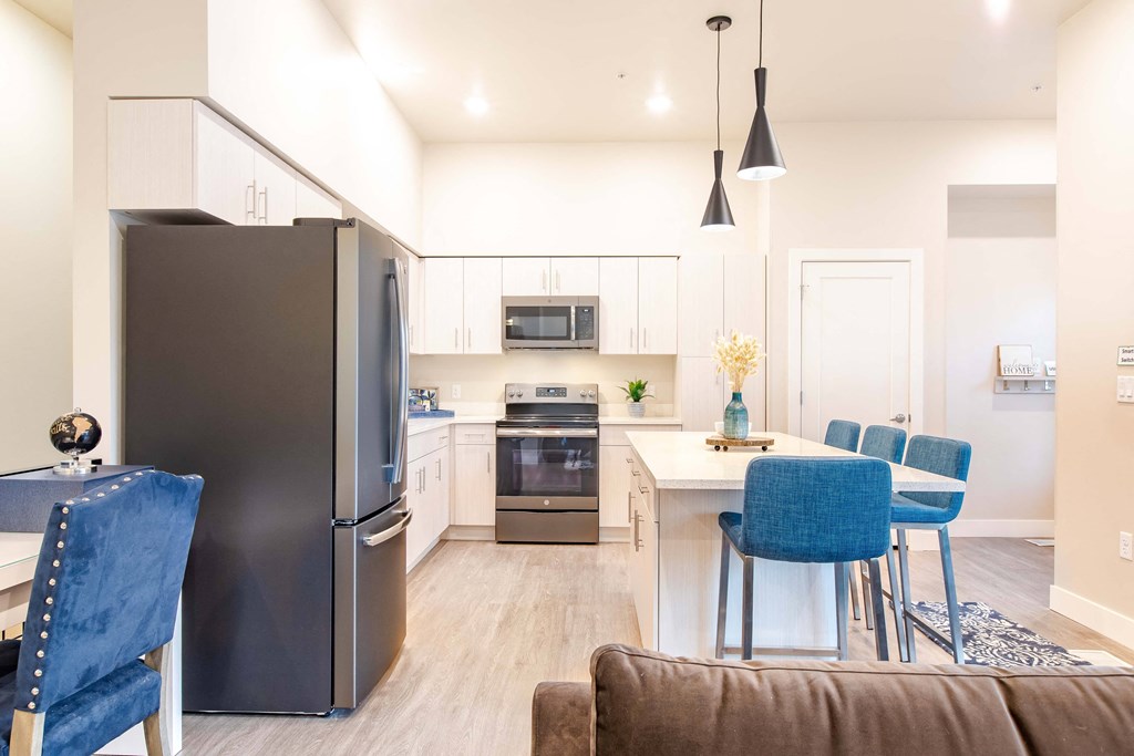 a kitchen and dining room with stainless steel appliances and blue chairs