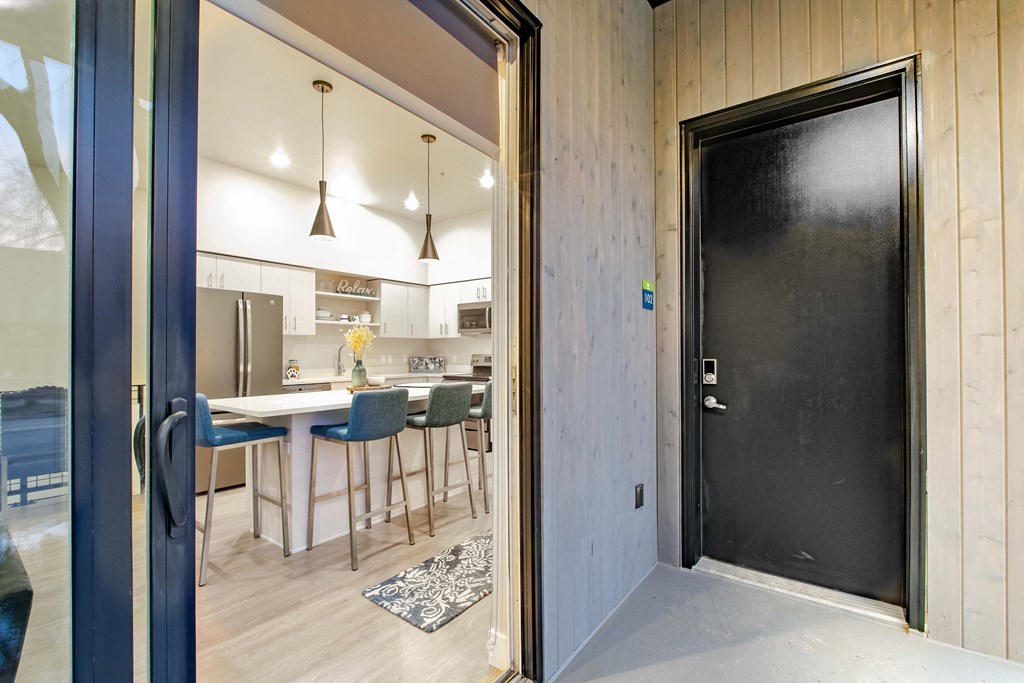 a door leading to a kitchen and dining area with a table and chairs