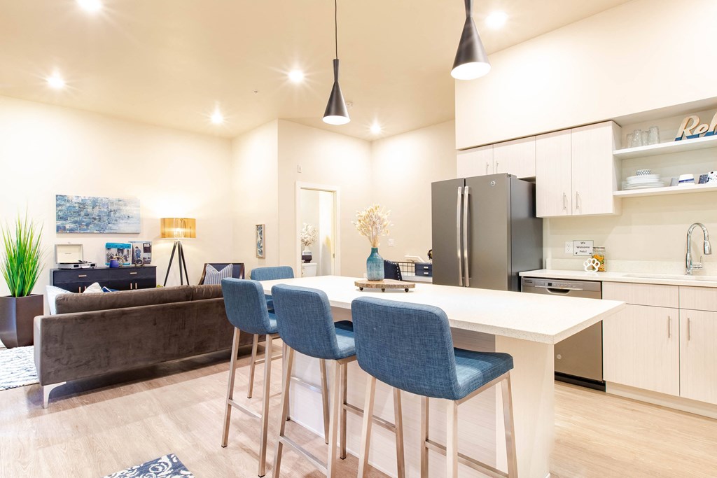 a kitchen and living room with a white counter and blue chairs