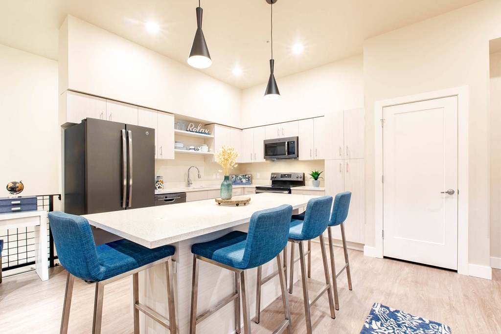 a kitchen with a white counter top and blue chairs