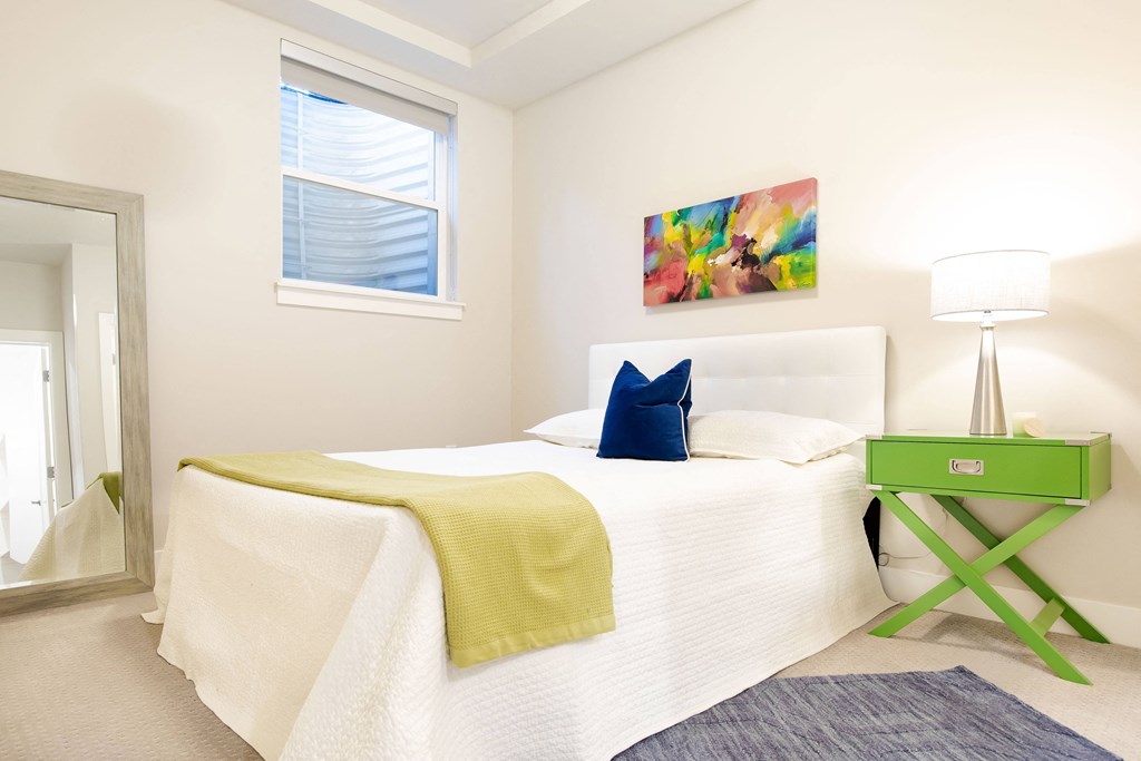 a bedroom with a white bed and a green nightstand