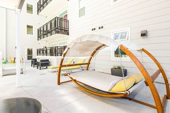 A wooden rocking chair with a white canopy is in the middle of a white room.