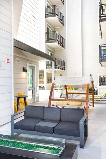 A grey couch is in the middle of a white room.