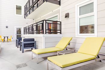 A patio with two yellow chairs and a table.