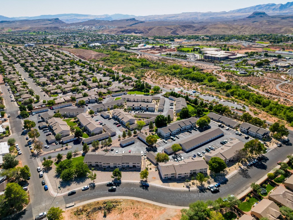 an aerial view of a city with houses and cars in a parking lot