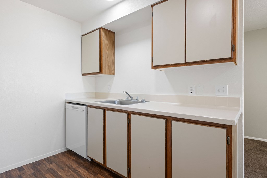 a kitchen with white appliances and wood flooring in an apartment