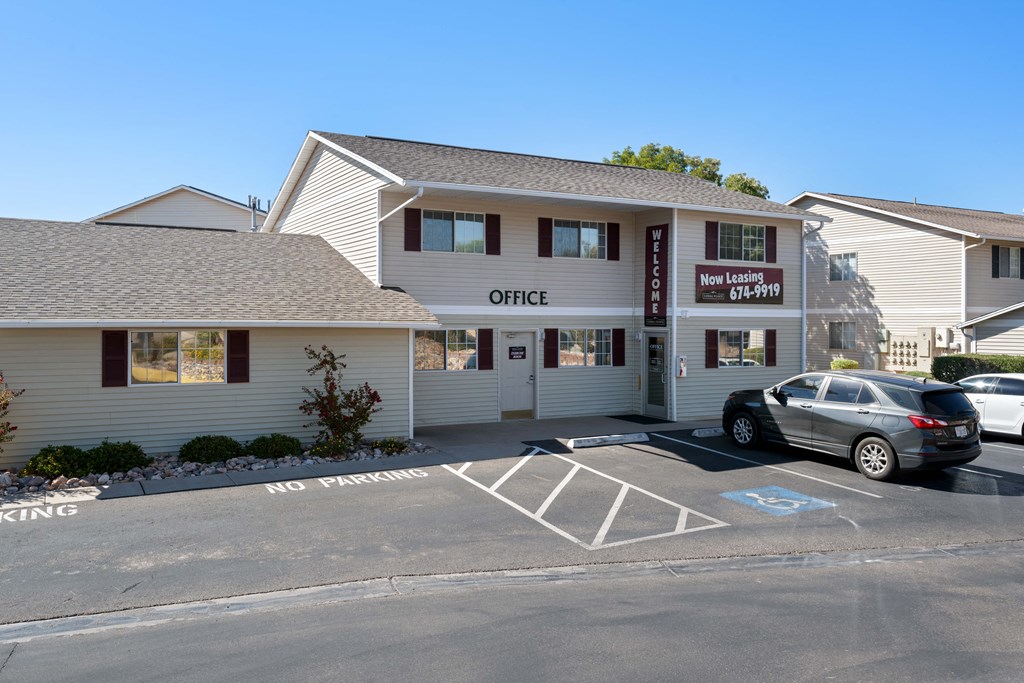 a white building with a parking lot and a car parked in front of it