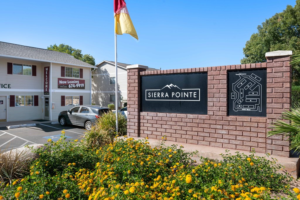 a brick building with a sign that reads sierra pointe and a yellow flag