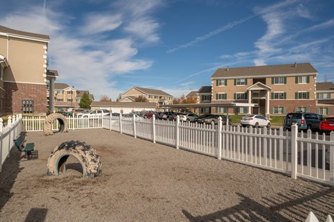 a fenced in dog park in front of a building