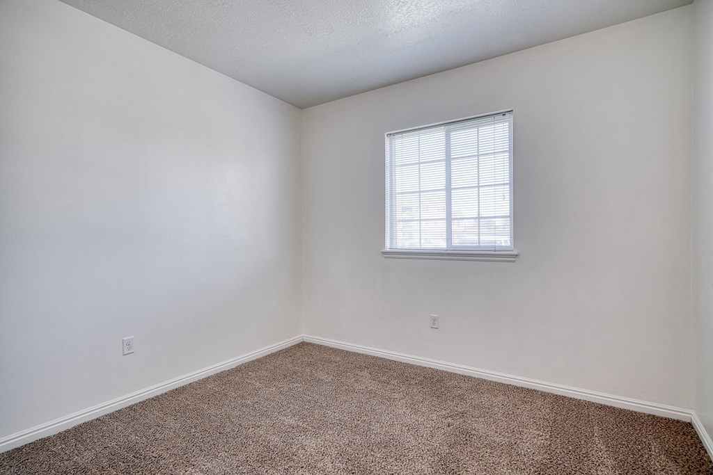 a bedroom with white walls and a window