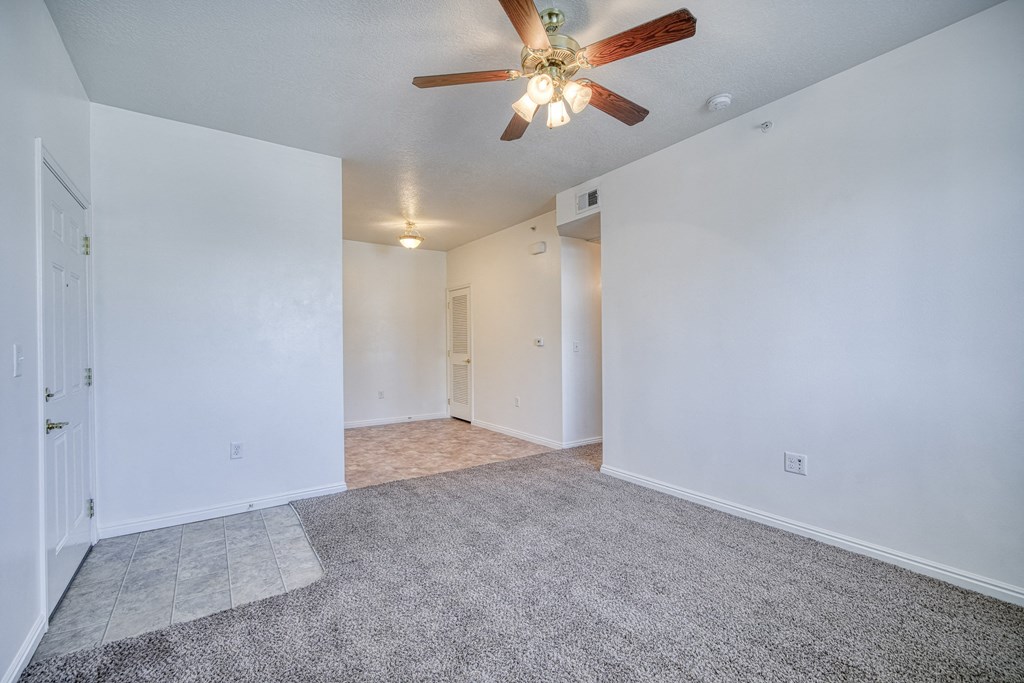 a bedroom with white walls and a ceiling fan