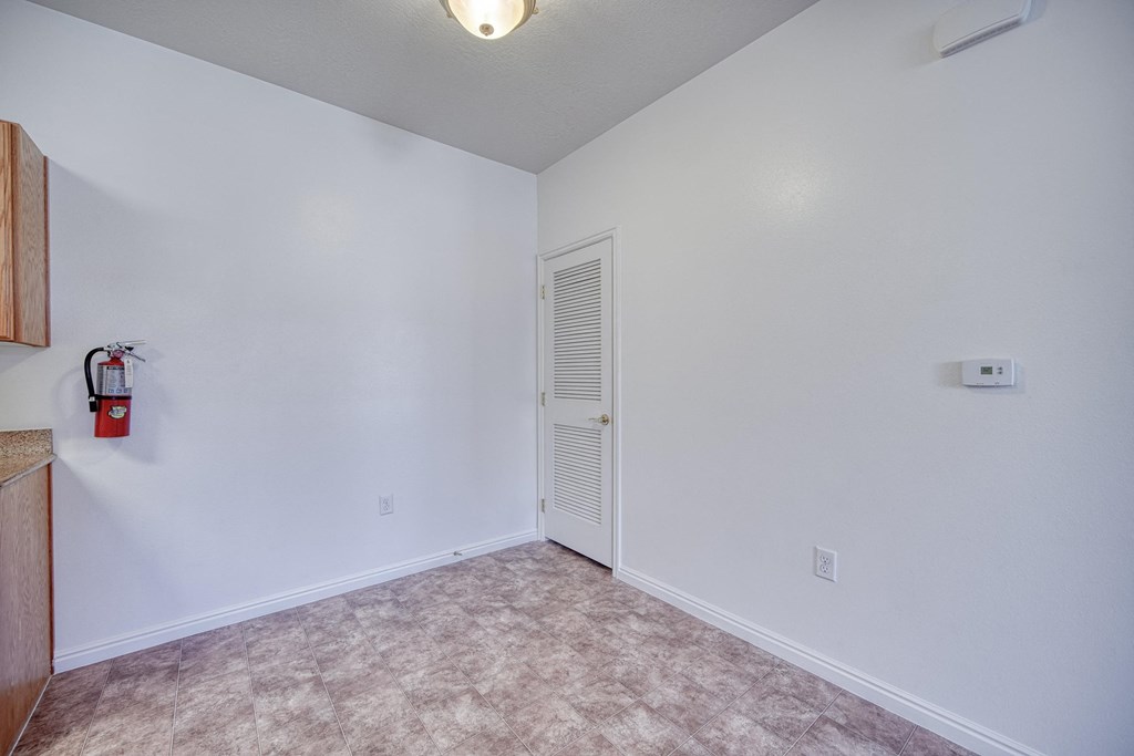 a bedroom with white walls and a white door with a fire extinguisher on the wall